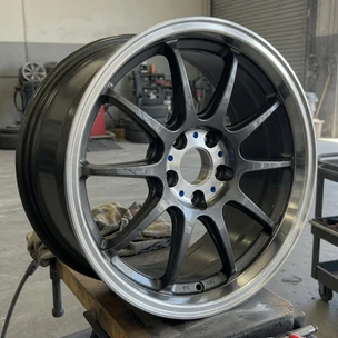 A polished aftermarket alloy wheel sits on a stand in an automotive workshop.